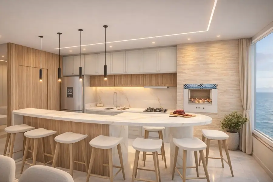 Cozinha gourmet com bancada de mármore em curva, churrasqueira revestida em pedra e janela ampla com vista para o mar.