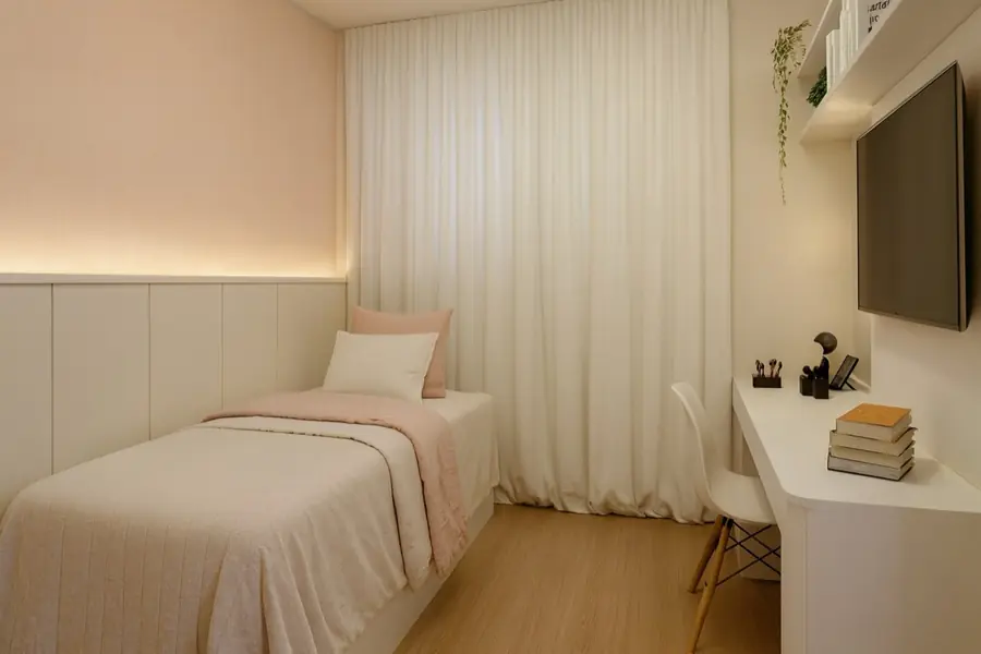 Cama de solteiro com manta rosa, parede em rosa claro, cortina longa branca e nicho com TV.