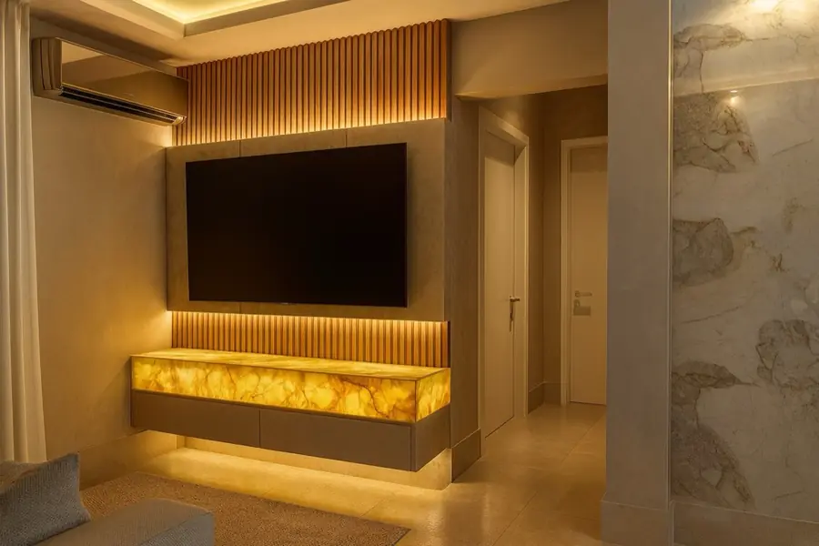 Painel de TV com ripas de madeira e rack em ônix retroiluminado em tom âmbar.