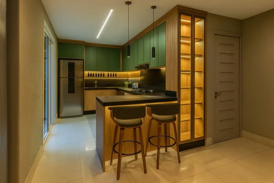 Cozinha pequena com armários em verde, bancada preta e cristaleira em madeira com luz interna.