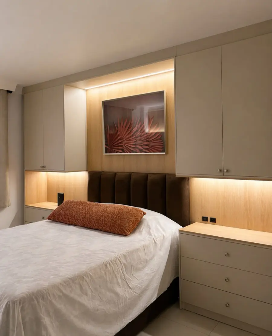 Cama com cabeceira estofada em veludo marrom, painel de madeira retroiluminado e quadro floral vermelho.